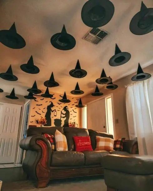 Witch hats displayed on a ceiling-mounted rack in a living room.