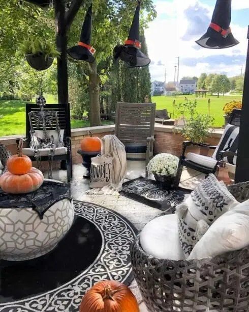 Outdoor patio with hanging witch hats and a skeleton in a chair.