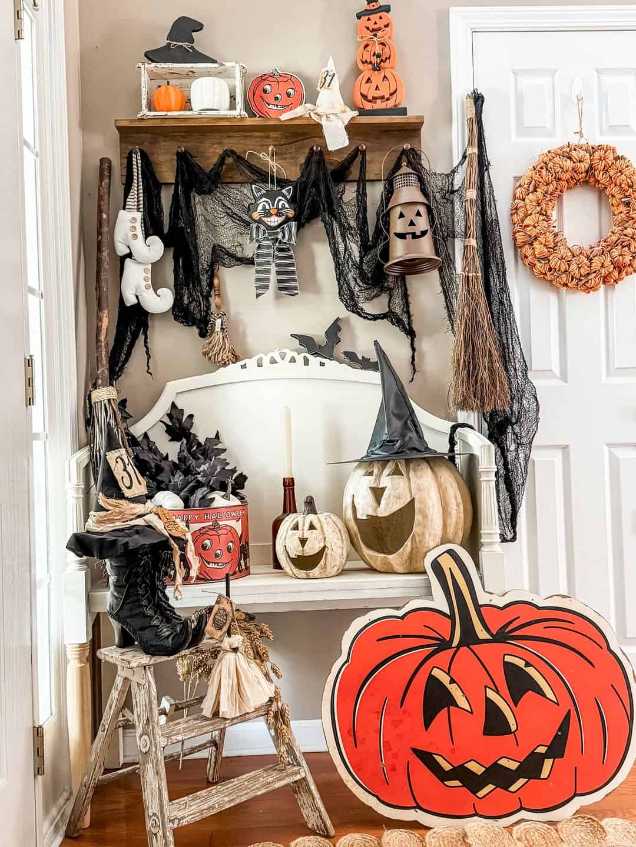 Vintage bench nook with witch boots, broom, and candles.