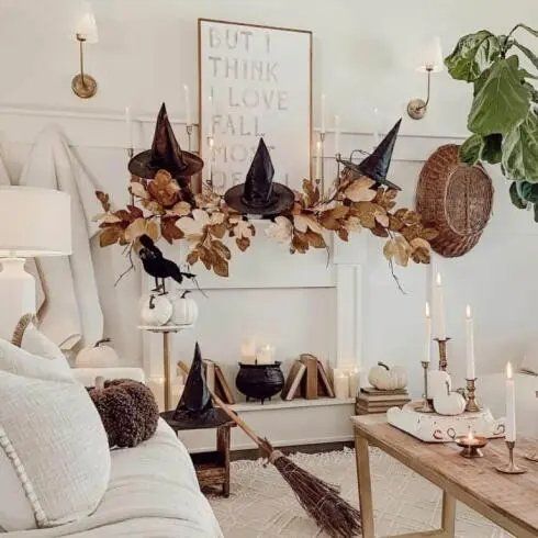White mantel with foliage, witch hats, and a small cauldron.