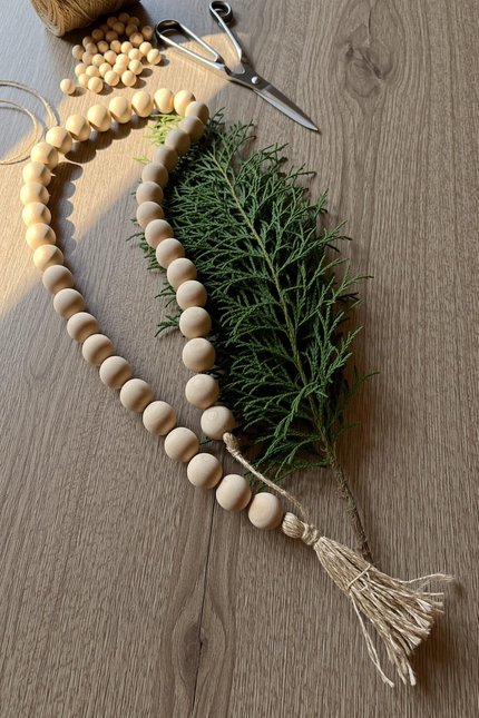 Minimalist Scandinavian living room mantel featuring natural wooden bead garland draped under fresh greenery