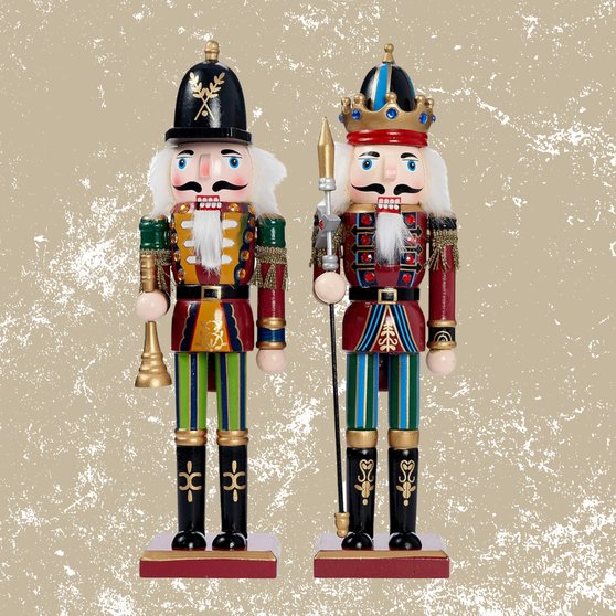 Pair of hand-painted wooden nutcrackers standing on a hearth with exposed brick and warm fireplace glow.