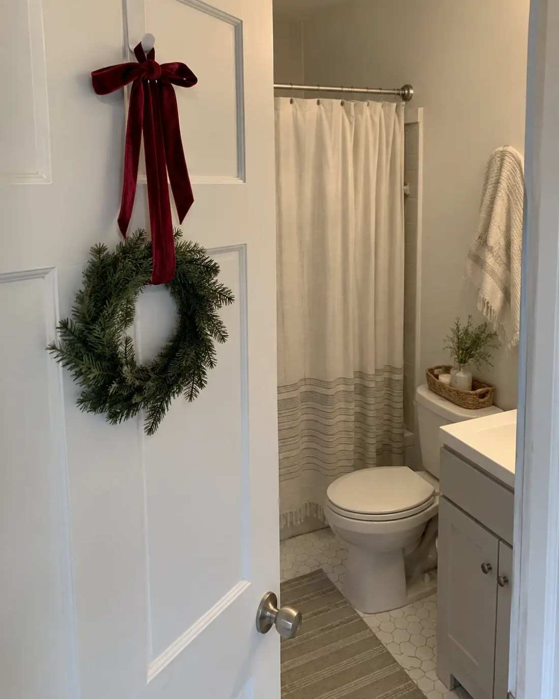 Wreath on back of door, white bathroom, festive entry accent, red bow