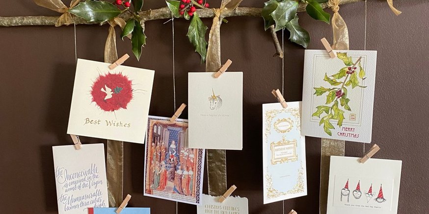 Vertical hanging jute strings with mini pine sprigs and holiday cards suspended from wall hook